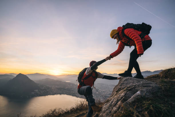 Young woman offers man a hand up, in the Swiss Alps